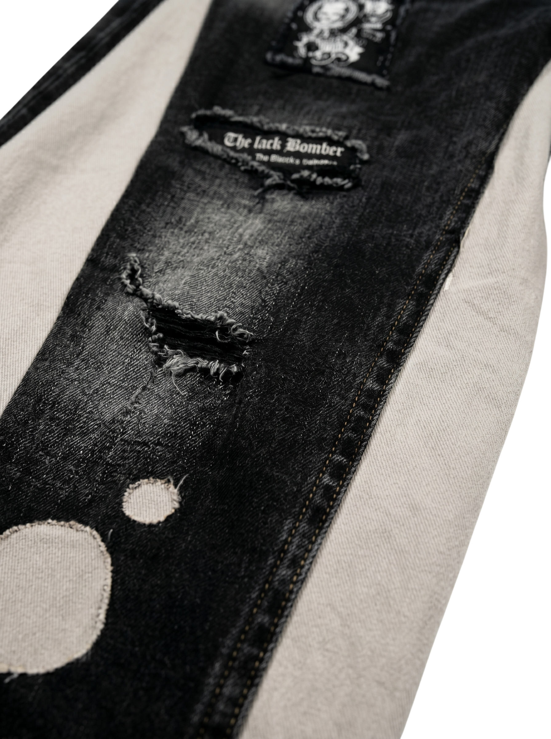 Close-up of a black distressed denim jacket with a brand label on a white background